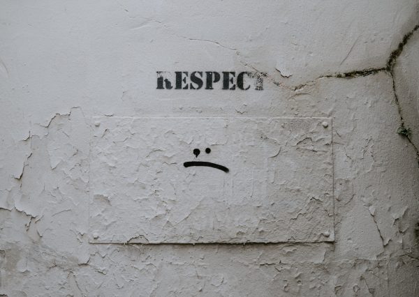 Wall showing graffiti that reads "respect" with a sad face below it